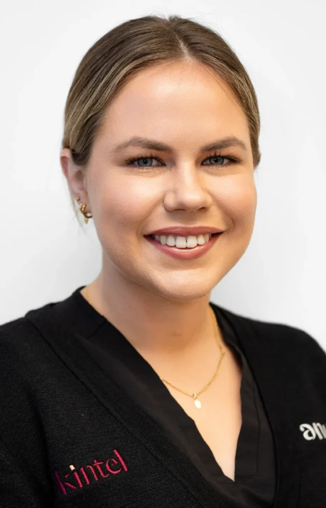 Claudia-manager - Anue Portrait of a smiling woman with blonde hair in a black cardigan, wearing a gold necklace, against a white background.
