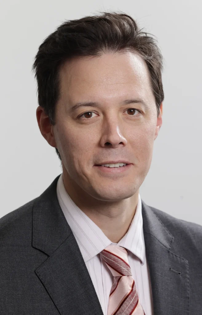 Dr-David-Lim - Anue Professional headshot of a man in a gray suit and pink striped tie, looking at the camera.