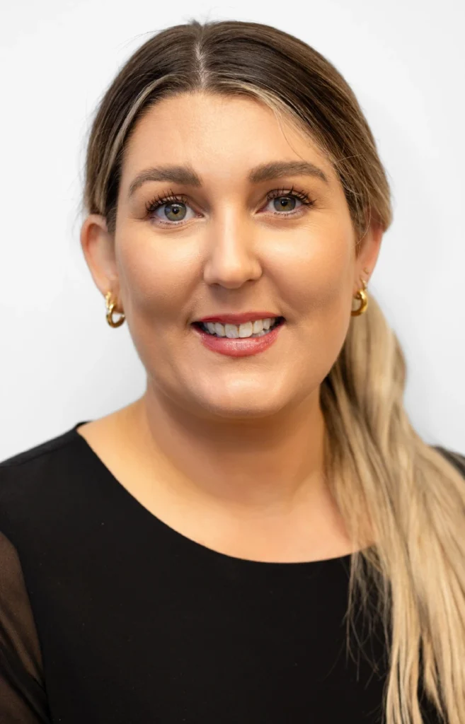 Lizzie-Reception - Anue Close-up portrait of a smiling woman with light makeup, gold hoop earrings, and a black top against a white background.